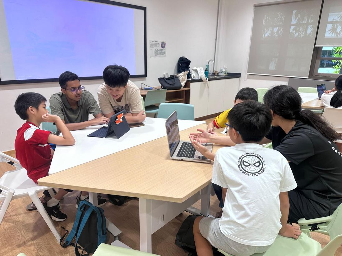 Children and volunteers working on laptops around a table