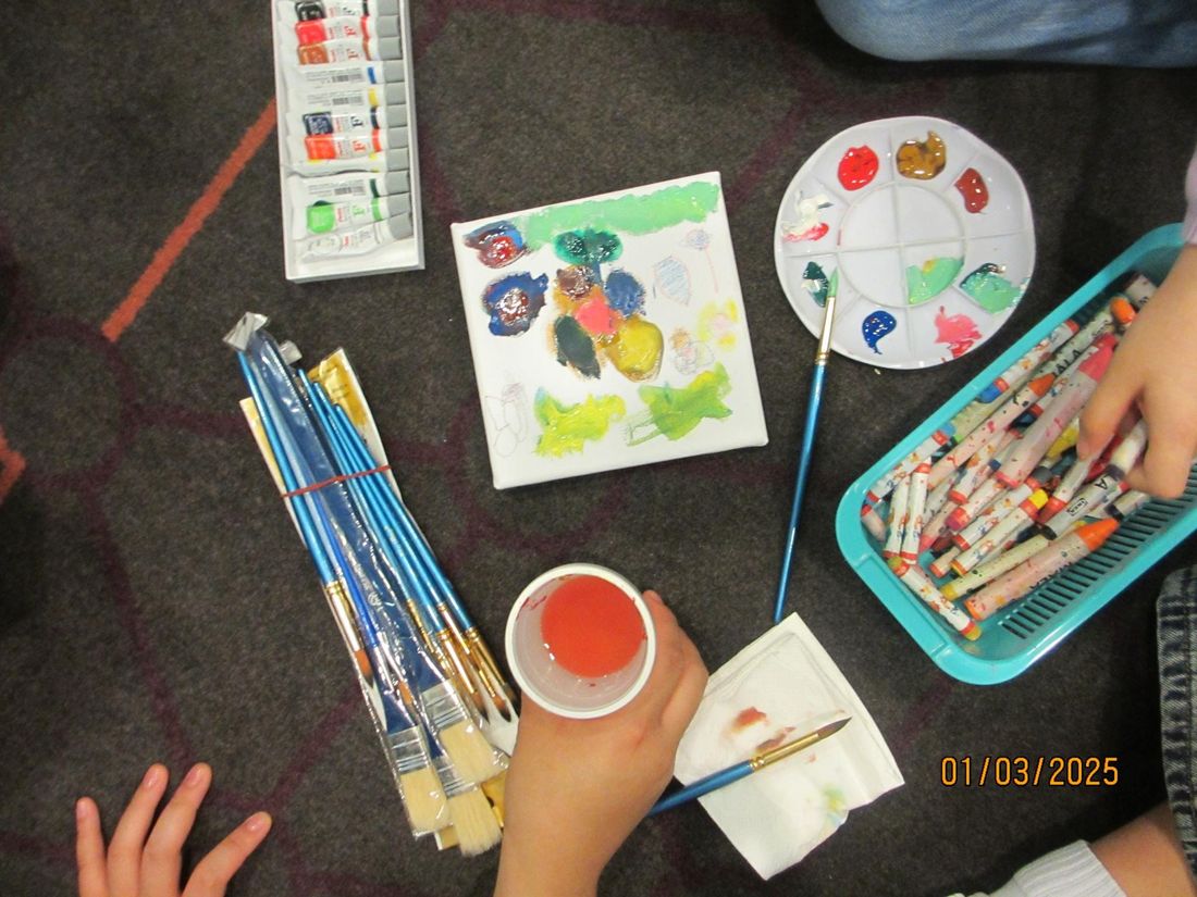 Watercolour paints, brushes and a child's painting on the floor
